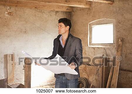 An architect reviewing blueprints at a building site View Large Photo Image Stock Photo - An architect reviewing blueprints at a building site. Fotosearch