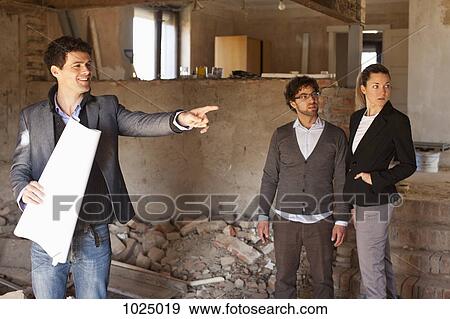 An architect showing a couple around a building site View Large Photo Image Stock Photo - An architect showing a couple around a building site. Fotosearch