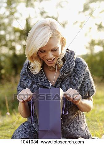 An excited woman looking into an open gift bag View Large Photo Image Picture - An excited woman looking into an open gift bag. Fotosearch