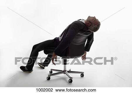 An exhausted businessman sleeping in an office chair View Large Photo Image Stock Image - An exhausted businessman sleeping in an office chair. Fotosearch