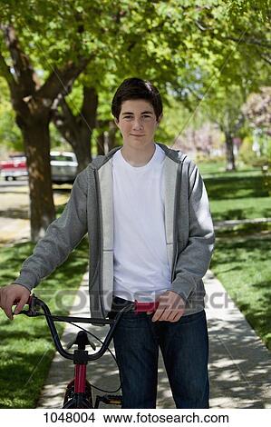 Picture - Boy holding bike to his side looking at camera. Fotosearch
