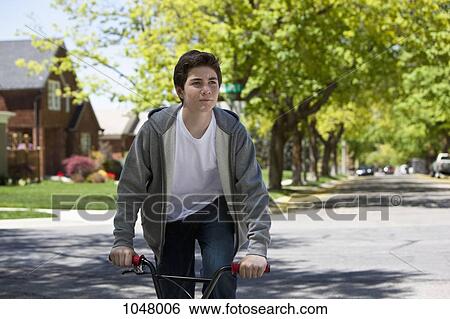 Boy standing while riding bike View Large Photo Image Stock Photograph - Boy standing while riding bike. Fotosearch