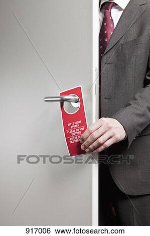 Stock Photograph - Businessman attaches 'do not disturb' sign. Fotosearch