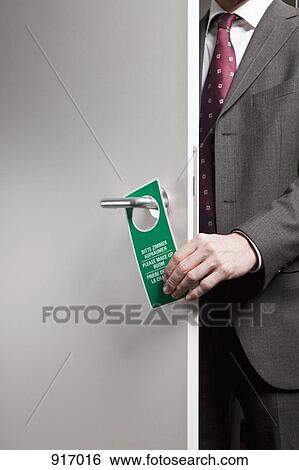 Businessman attaches 'please make up room' sign View Large Photo Image Stock Photograph - Businessman attaches 'please make up room' sign. Fotosearch