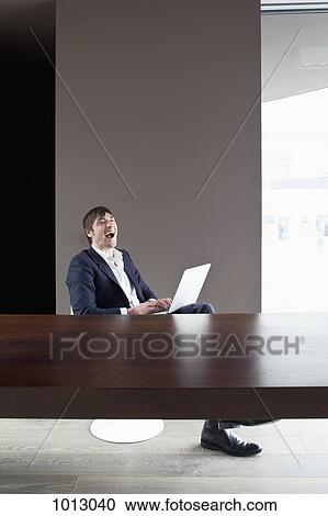 Stock Image - Businessman on laptop enjoys working from home.. Fotosearch