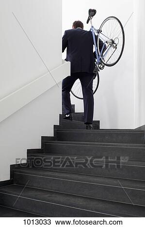 Businessman returns home carrying his bicycle up steps View Large Photo Image Stock Image - Businessman returns home carrying his bicycle up steps. Fotosearch