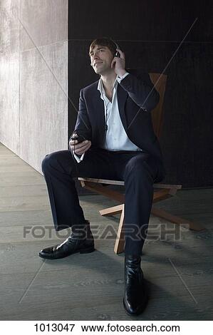 Businessman sitting on chair listening to headphones. View Large Photo Image Stock Photo - Businessman sitting on chair listening to headphones.. Fotosearch