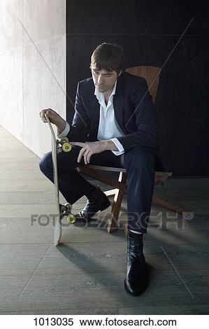 Stock Photography - Businessman sitting touching skateboard wheel and thinking.. Fotosearch