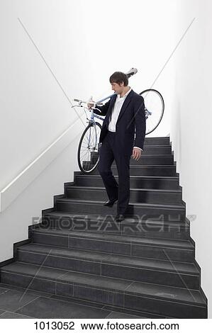Businessman walking down steps carrying bicycle. View Large Photo Image Stock Image - Businessman walking down steps carrying bicycle.. Fotosearch