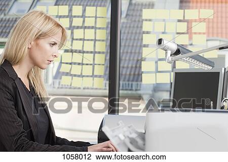 Businesswoman concentrating as she types on office computer View Large Photo Image Stock Image - Businesswoman concentrating as she types on office computer. Fotosearch
