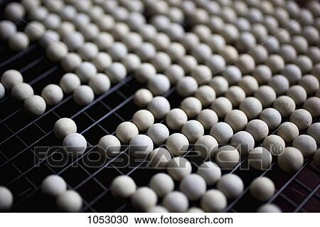 Stock Image - Ceramic pie weights lined up on a metal rack. Fotosearch