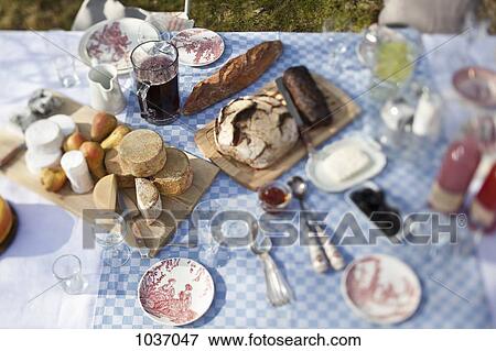 cheese wheels, bread and a lot of crockery on a dining table outside View Large Photo Image Stock Photo - cheese wheels, bread and a lot of crockery on a dining table outside. Fotosearch