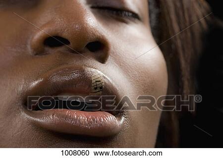 Stock Image - Close-up of a woman with a musical note on her lip. Fotosearch