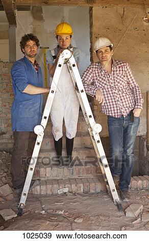 Construction workers leaning on a ladder at a building site View Large Photo Image Stock Photo - Construction workers leaning on a ladder at a building site. Fotosearch