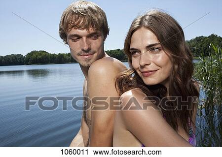 Couple back to back beside the lake View Large Photo Image Stock Image - Couple back to back beside the lake. Fotosearch