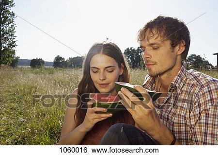 Couple in field eating a melon View Large Photo Image Stock Photograph - Couple in field eating a melon. Fotosearch
