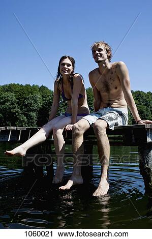 Couple side by side on jetty dipping feet in lake View Large Photo Image Stock Image - Couple side by side on jetty dipping feet in lake. Fotosearch
