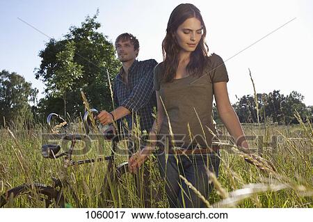 Couple walk amongst the timothy grass with bike View Large Photo Image Stock Photo - Couple walk amongst the timothy grass with bike. Fotosearch