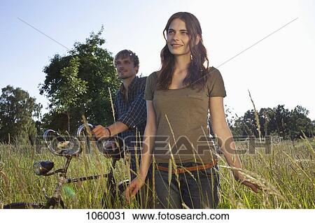 Couple walk through timothy grass with bike View Large Photo Image Stock Image - Couple walk through timothy grass with bike. Fotosearch