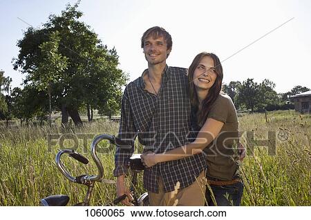 Couple walking through field with bike View Large Photo Image Stock Photography - Couple walking through field with bike. Fotosearch