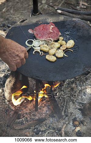 Detail of a man cooking food over a campfire View Large Photo Image Stock Photograph - Detail of a man cooking food over a campfire. Fotosearch