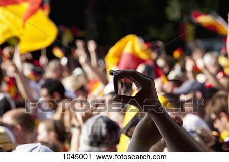 Detail of a person in a crowd holding a mobile phone View Large Photo Image Stock Image - Detail of a person in a crowd holding a mobile phone. Fotosearch