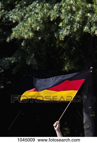 Stock Photo - Detail of a person waving a German flag. Fotosearch