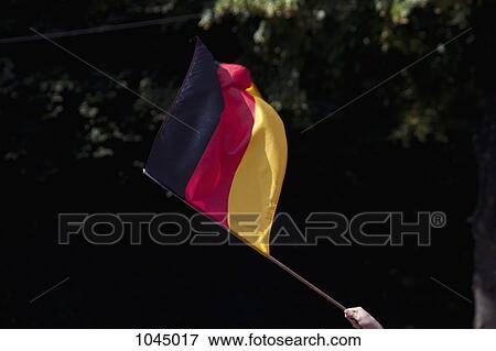 Stock Photo - Detail of a person waving a German flag. Fotosearch
