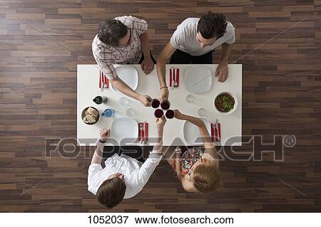 Four friends toasting at a dinner party, overhead view View Large Photo Image Stock Photo - Four friends toasting at a dinner party, overhead view. Fotosearch