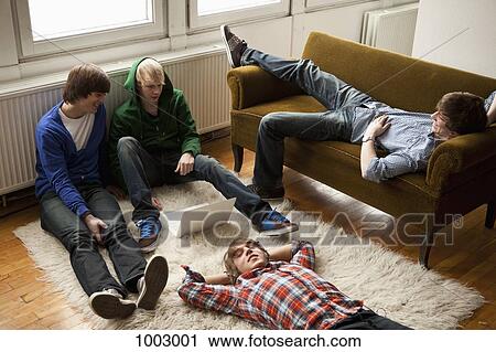 Four teenage friends hanging out in a living room View Large Photo Image Stock Image - Four teenage friends hanging out in a living room. Fotosearch