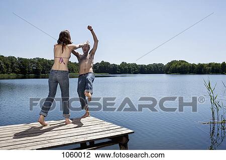Girl on jetty pushes guy into water View Large Photo Image Stock Image - Girl on jetty pushes guy into water . Fotosearch