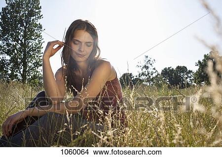 Girl sitting amongst timothy grass touching her hair View Large Photo Image Picture - Girl sitting amongst timothy grass touching her hair. Fotosearch