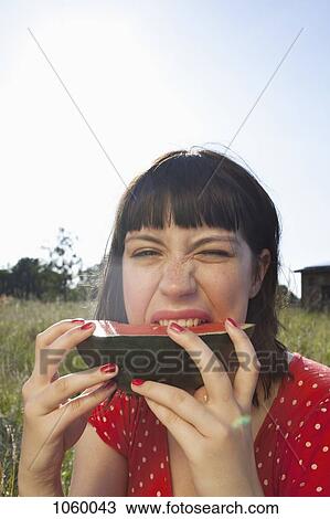 Girl takes a bite of her slice of melon while sitting in the field View Large Photo Image Stock Image - Girl takes a bite of her slice of melon while sitting in the field. Fotosearch