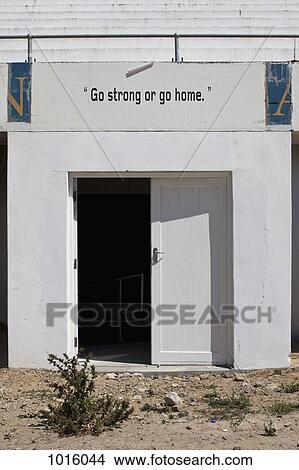 Picture - 'Go strong or go home' sign above door.. Fotosearch