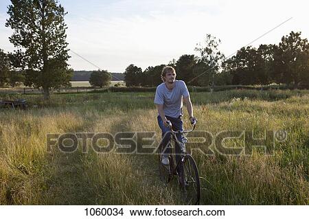Guy cycles through secluded field on bike View Large Photo Image Picture - Guy cycles through secluded field on bike. Fotosearch
