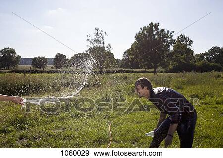 Guy ducks for cover as he gets sprayed with hose View Large Photo Image Stock Photo - Guy ducks for cover as he gets sprayed with hose. Fotosearch
