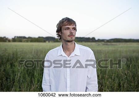 Guy in white shirt looks to the side in field View Large Photo Image Stock Image - Guy in white shirt looks to the side in field. Fotosearch