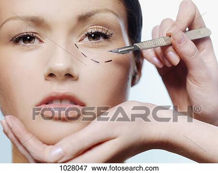 Hands holding a scalpel and a woman's face with a dotted line under her eye View Large Photo Image Stock Photo - Hands holding a scalpel and a woman's face with a dotted line under her eye. Fotosearch