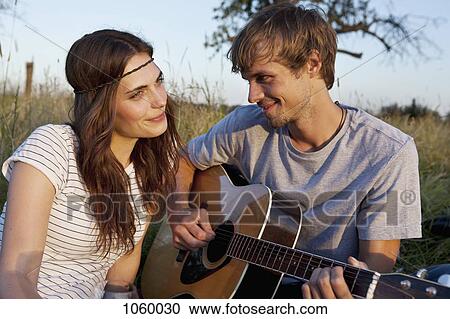 Man plays guitar to his girlfriend in field View Large Photo Image Stock Image - Man plays guitar to his girlfriend in field. Fotosearch