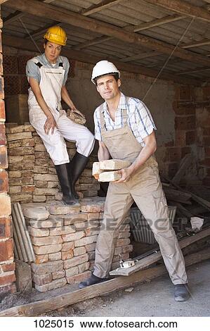 Stock Photography - Manual workers moving bricks at a building site. Fotosearch