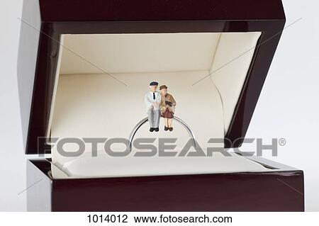Miniature figurines of a senior woman and senior man sitting together on a wedding ring View Large Photo Image Stock Image - Miniature figurines of a senior woman and senior man sitting together on a wedding ring. Fotosearch
