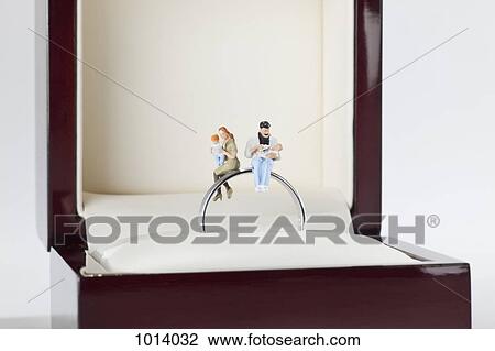 Miniature figurines of a young family sitting on a wedding ring in a jewelry box View Large Photo Image Stock Image - Miniature figurines of a young family sitting on a wedding ring in a jewelry box. Fotosearch