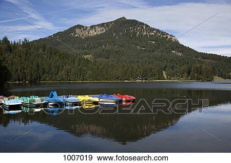 Pedal boats on a lake and a mountain in the background View Large Photo Image Stock Photo - Pedal boats on a lake and a mountain in the background. Fotosearch