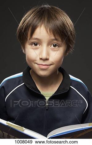 Portrait of a boy holding an open book View Large Photo Image Stock Photo - Portrait of a boy holding an open book. Fotosearch