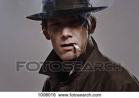 Portrait of a man wearing a hat and trench coat while smoking View Large Photo Image Stock Photograph - Portrait of a man wearing a hat and trench coat while smoking. Fotosearch