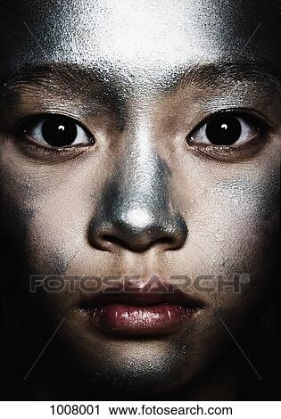 Stock Image - Portrait of a teenage girl with silver paint on her face. Fotosearch
