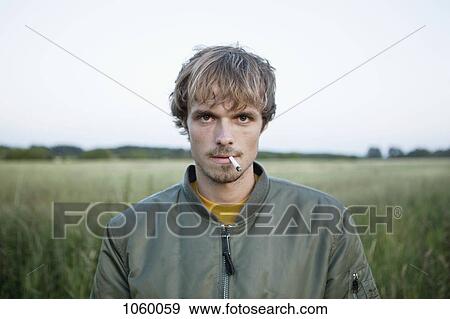 Profile of man standing in secluded field with cigarette hanging out of his mouth View Large Photo Image Stock Photo - Profile of man standing in secluded field with cigarette hanging out of his mouth. Fotosearch