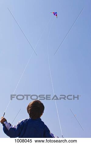Rear view of a boy flying a kite View Large Photo Image Stock Photography - Rear view of a boy flying a kite. Fotosearch