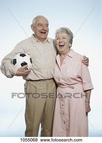 Senior couple laughing as man holds football View Large Photo Image Stock Photo - Senior couple laughing as man holds football. Fotosearch