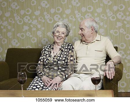 Senior couple relaxed on couch with two glasses of wine on the table View Large Photo Image Stock Photo - Senior couple relaxed on couch with two glasses of wine on the table. Fotosearch